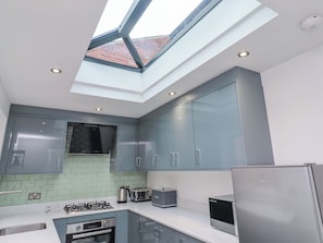 A modern kitchen with a skylight, stainless steel appliances, and grey cabinetry. - Middle Cottage (Alnwick)