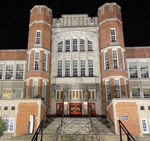 A large building with a symmetrical facade, multiple windows, and a central entrance with steps leading up to it.