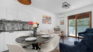 Une cuisine moderne avec des meubles blancs, un coin repas doté d’une table ronde et un canapé.