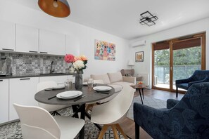 Eine moderne Küche mit weißen Schränken, ein Essbereich mit einem runden Tisch und eine Sitzecke mit einer Couch.