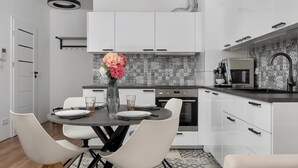 Une cuisine moderne avec des armoires blanches, un plan de travail noir et un pare-feu décoré d’un motif.