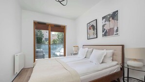 Une chambre dotée d’un grand lit, d’une fenêtre offrant une belle vue et de deux œuvres d’art accrochées au mur.