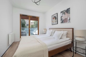 Ein Schlafzimmer mit einem großen Bett, einem Fenster mit Ausblick und zwei an der Wand befestigten Kunstwerken.