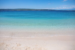 A beach with clear water, sandy shore, and distant land. - Modern vacation apartment with swimming pool and barbecue facilities (Crikvenica)
