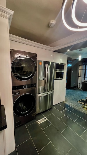 Cocina moderna con electrodomésticos de acero inoxidable, incluyendo un refrigerador, microondas y lavadora.