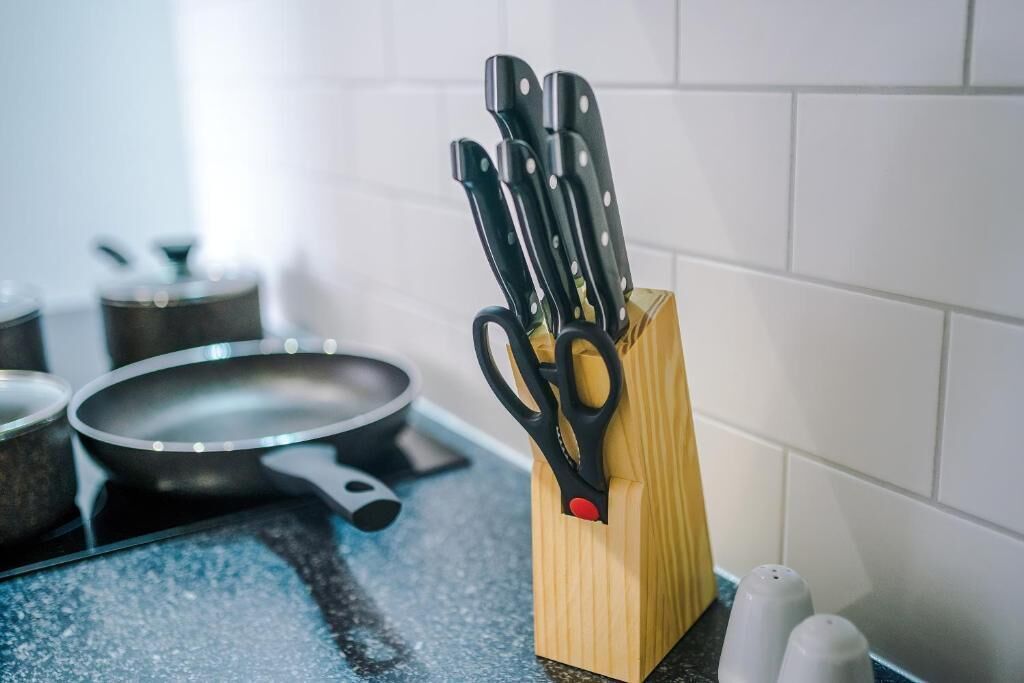 Een keukentrap met een messenblok, een koekenpan, zout- en pepervaatjes, en een pan.
