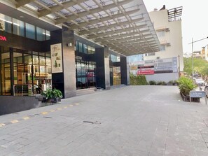 Um edifício com entrada coberta, um letreiro com 'LANCASHER' e uma placa 'LÔI RA' indicando uma saída.