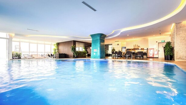 An indoor swimming pool with a central column, lounge chairs, and a reception area. - City Centre Apartment - Lancaster Hanoi (Hanoi)