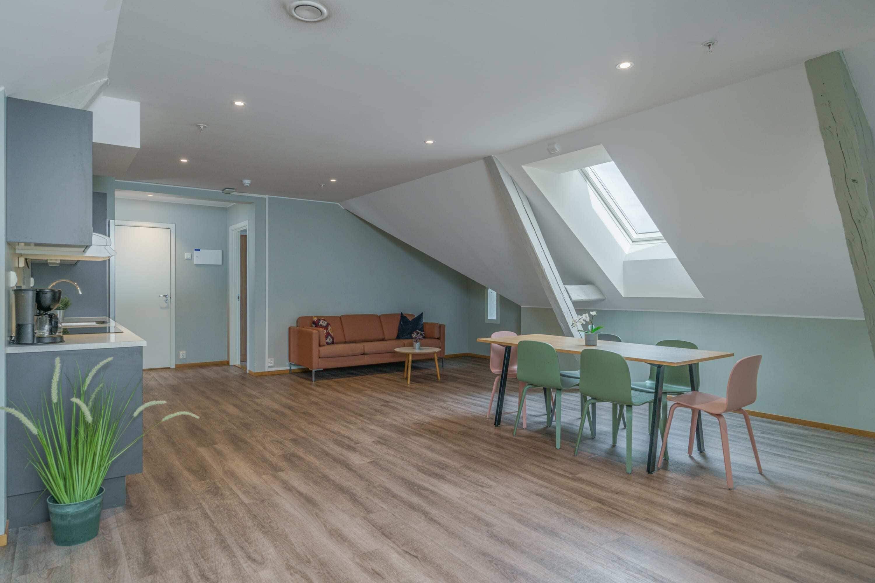 A modern loft-style room with a dining area, a sofa, and a skylight.
