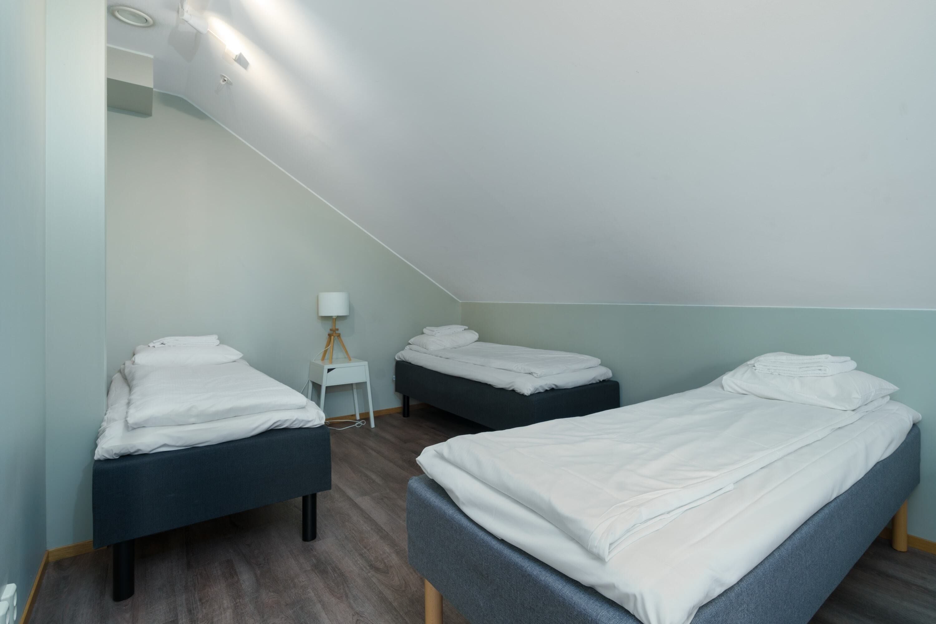 A room with two beds, a small table, and a lamp.