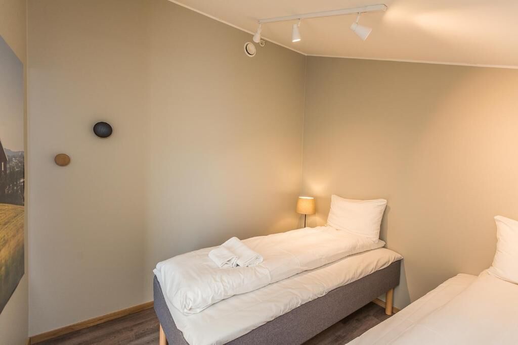Een kamer met twee bedden, een wandlamp en een plafondarmatuur.