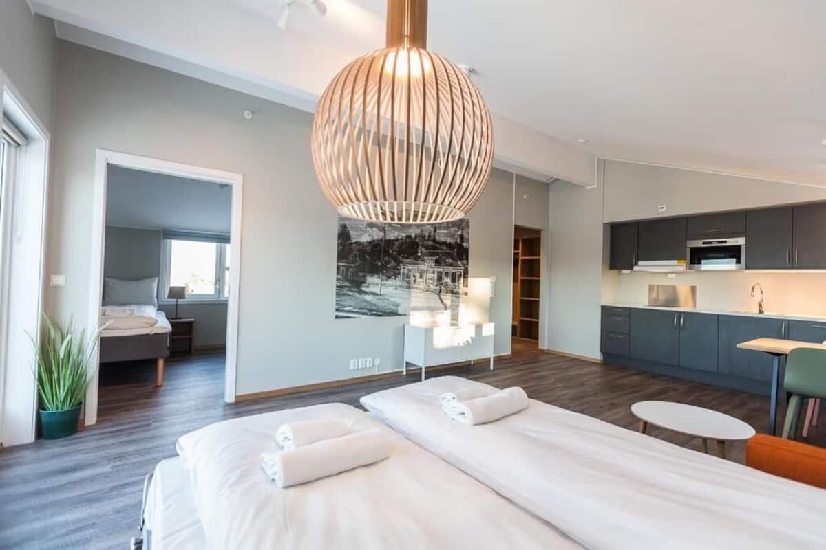Quarto de hotel moderno com uma cama grande, uma escrivaninha pequena, uma cozinha compacta e uma janela ampla.