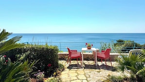 Eine Terrasse mit Tisch und Stühlen mit Blick auf das Meer.