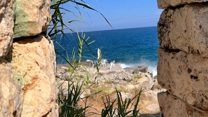 Ein steinerer Bogen rahmt den Blick auf das Meer und den Strand.