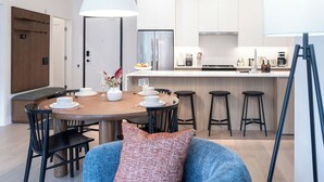 Cozinha moderna com armários brancos, uma ilha central e banquetas de bar.