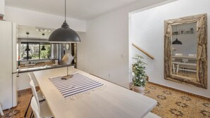 Ett modernt kök med ett träbord, en hängande taklampa och en rustik spegel.