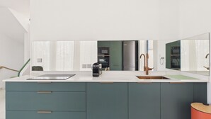 Una cocina moderna con una isla grande, electrodomésticos de acero inoxidable y un espejo amplio.