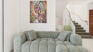 Una sala de estar moderna con un sofá verde, una escalera de madera y una obra de arte colgada en la pared.