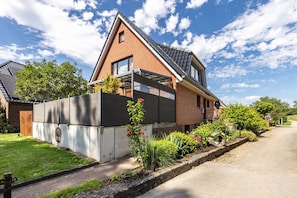 A residential house with a sloped roof, a brick exterior, and a garden with various plants and flowers. - Apartment 'Gemütliche' with Private Terrace and Wi-Fi (Scharbeutz)