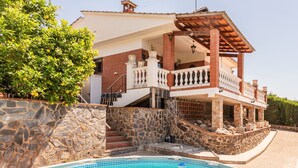 Una casa con piscina, paredes de piedra y un balcón.