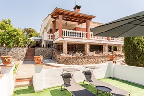 A two-story house with a balcony, outdoor seating, and a stone wall. - Holiday Home 'Villa Toro' with Mountain Views, Wi-Fi and Air Conditioning (Maçanet de la Selva)