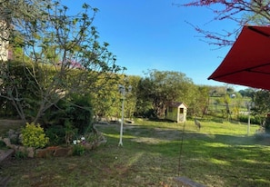 A garden with a small shed, a swing set, and a red umbrella. - Apartment - 1 bedroom - Villevieille (Villevieille)
