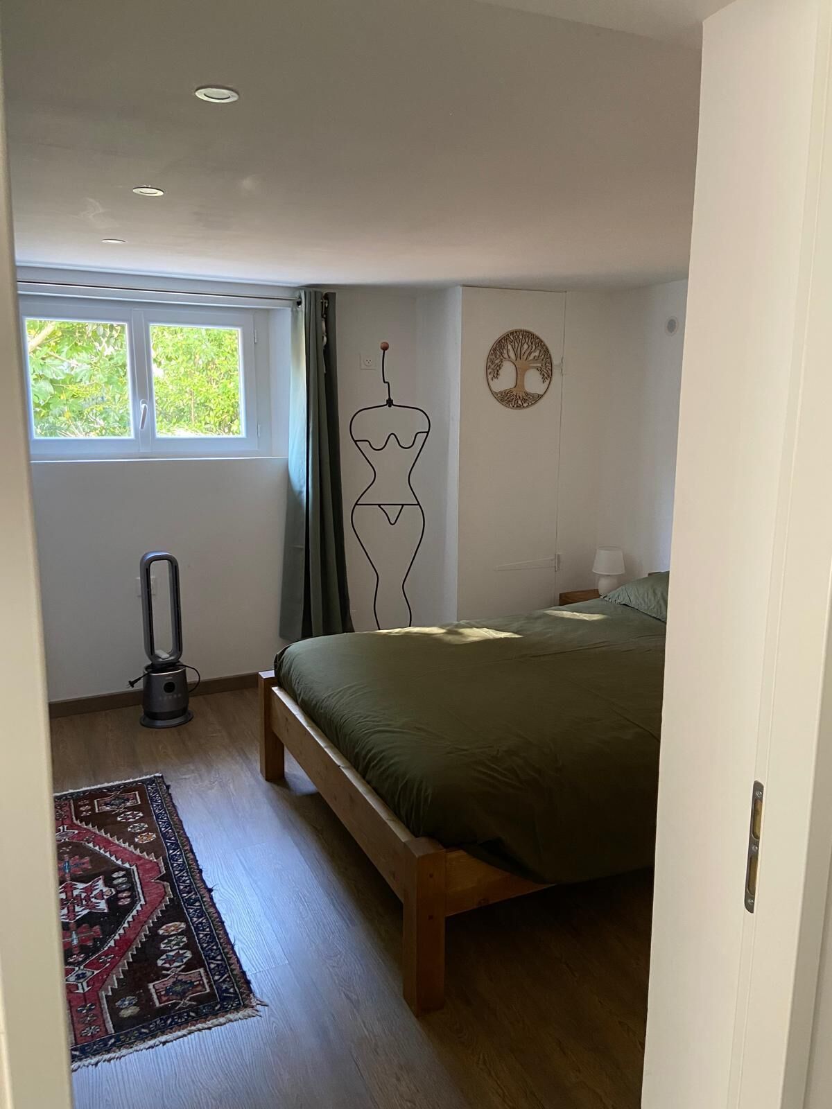 A bedroom with a bed, a heater, a window, and a wall decoration.