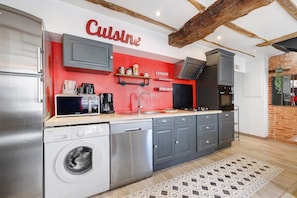 A modern kitchen with grey cabinets, a dishwasher, a washing machine, a red accent wall, and a hanging light fixture. - Apartment 'Les Glycines N2' with Private Terrace, Balcony and Wi-Fi (Les Epesses)