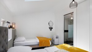 Un dormitorio con dos camas, una mesita de noche, un armario, una lámpara colgante y una ventana.
