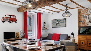 Un comedor con mesa de madera, sillas y una cortina roja.