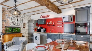 Una cocina moderna con una pared de acento roja, un comedor con mesa de madera y una silla estampada de cuadros de dintel.