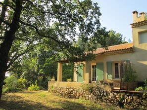 Ein Haus mit einer Steinwand, grünen Fensterläden und einem Ziegeldach.