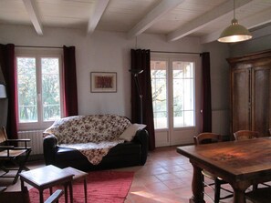 Ein Zimmer mit einer Couch, einem Esstisch und einem Fenster mit Vorhängen.