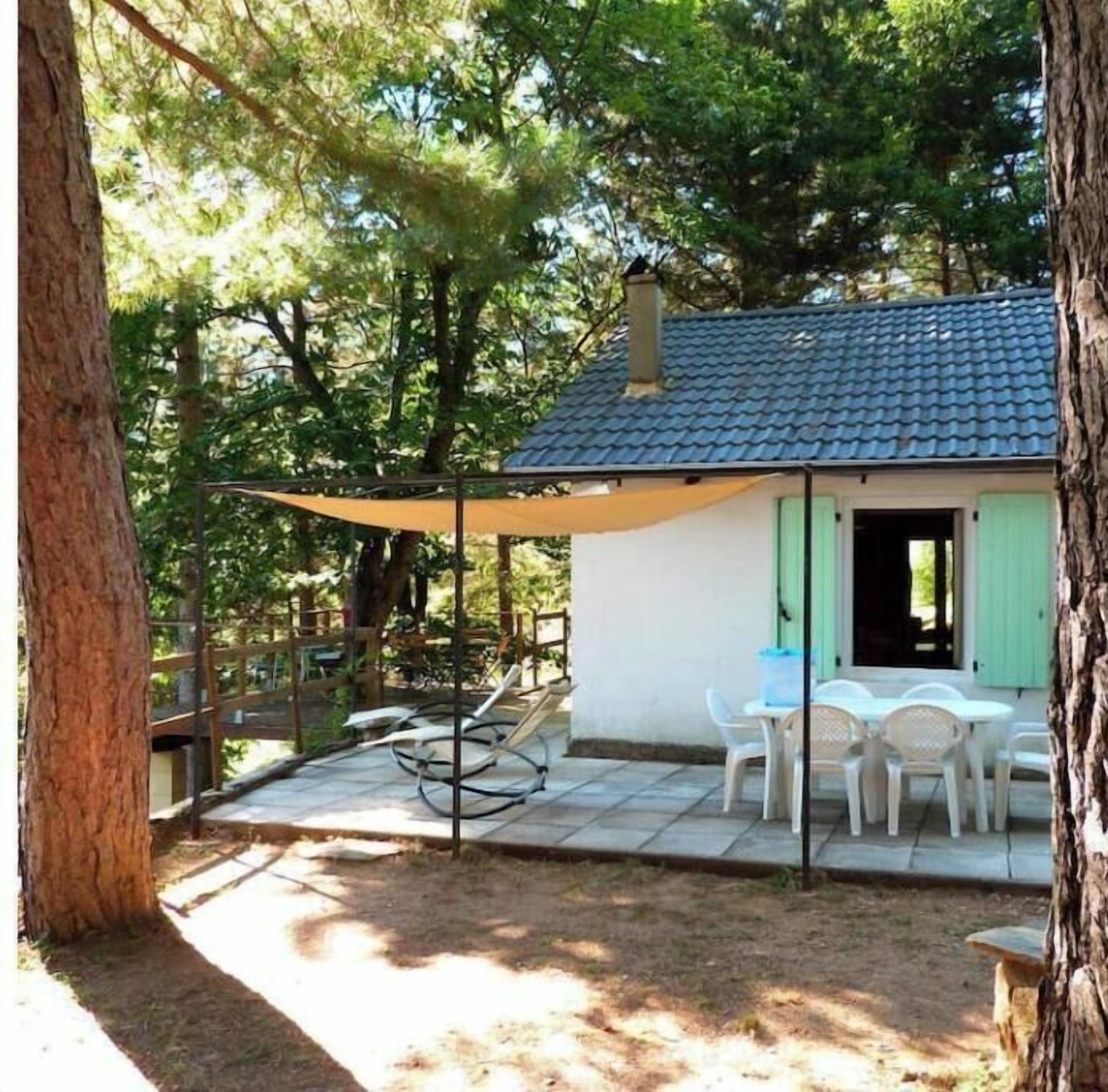 Une petite maison avec un toit en tuiles, une terrasse avec des chaises et une plateforme en bois.