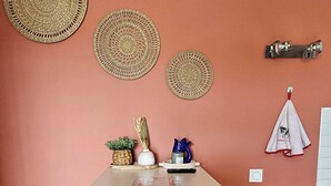 Een eethoek met een tafel, vier stoelen, een prullenbak en decoratieve wandversieringen.