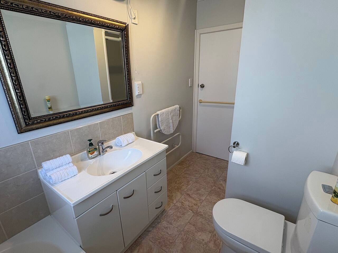A bathroom with a white sink, mirror, and toilet.