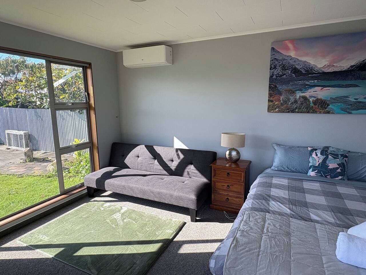 Une chambre avec un canapé, un lit, une lampe et un tableau au mur.