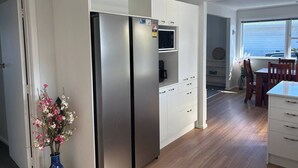 A modern kitchen with a built-in refrigerator, white cabinetry, and a dining area with a table and chairs.