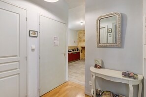 Un pasillo con puertas blancas, un espejo y una pequeña mesa con revistas.