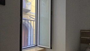 Un dormitorio con un ventanal grande, una cama, una mesita con toallas y una escalera que lleva a un balcón al aire libre.