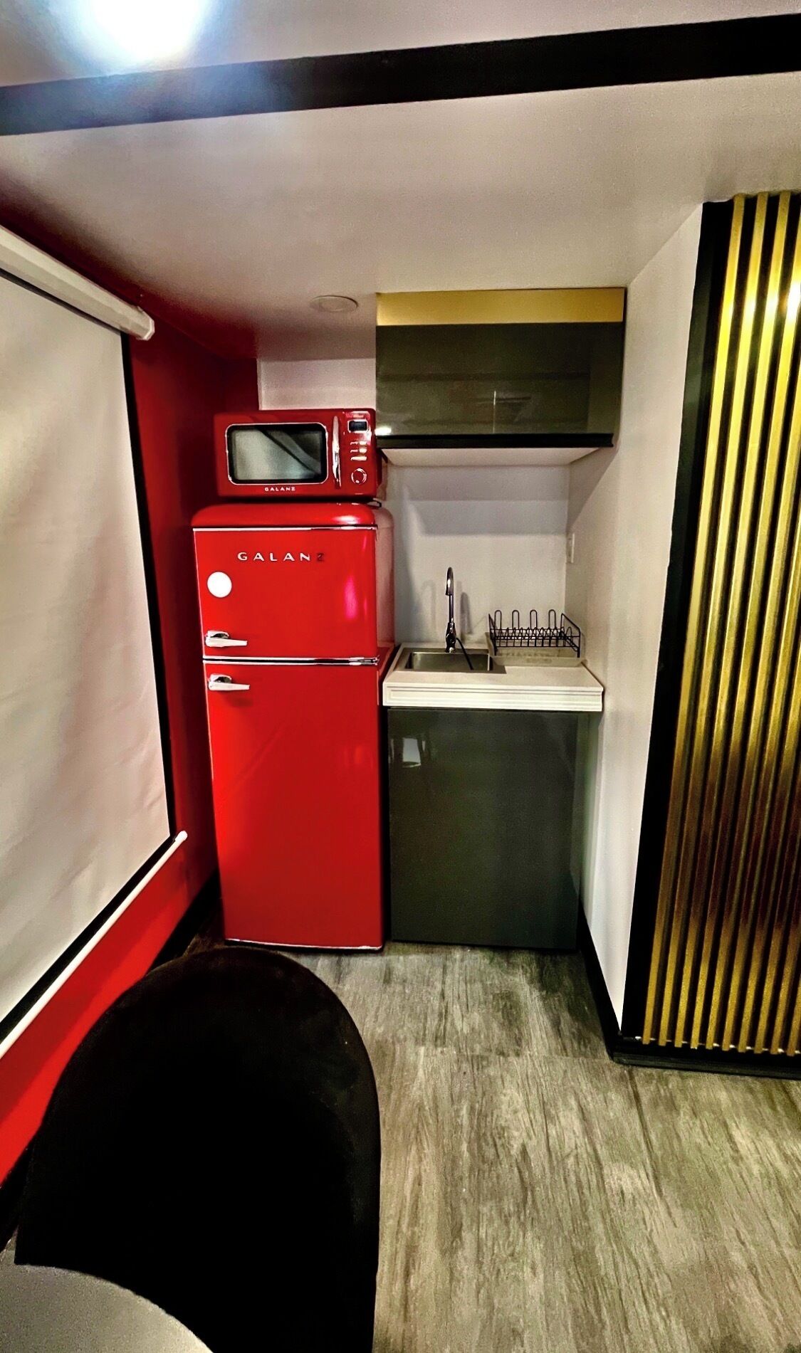 A compact kitchenette with a red refrigerator, a microwave, and a sink.