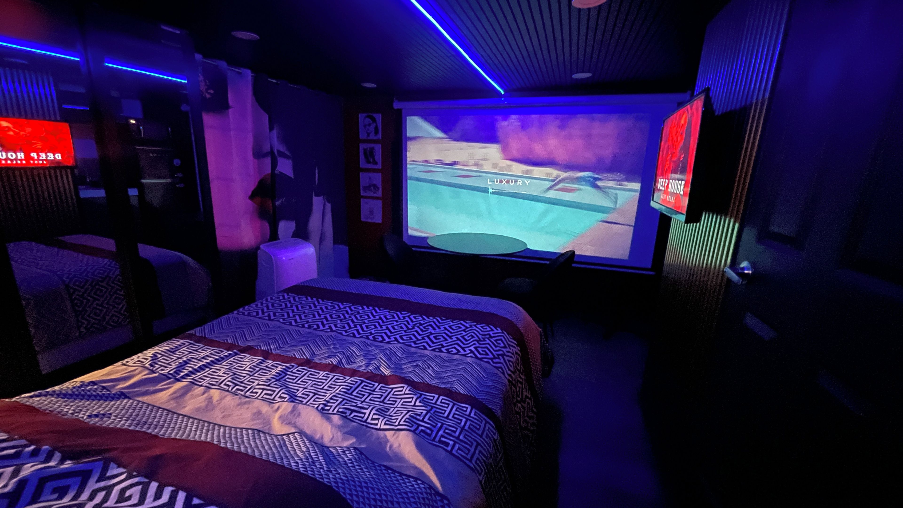 Une chambre d’hôtel avec un grand lit, un écran de télévision et un téléviseur fixé au mur.