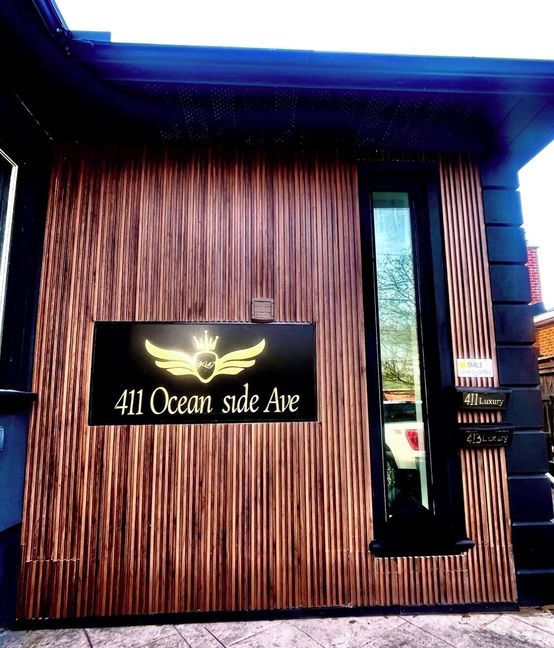 Eine Gebäudefassade mit vertikalen Holzlatten und einem Schild mit der Aufschrift '411 Ocean side Ave.'