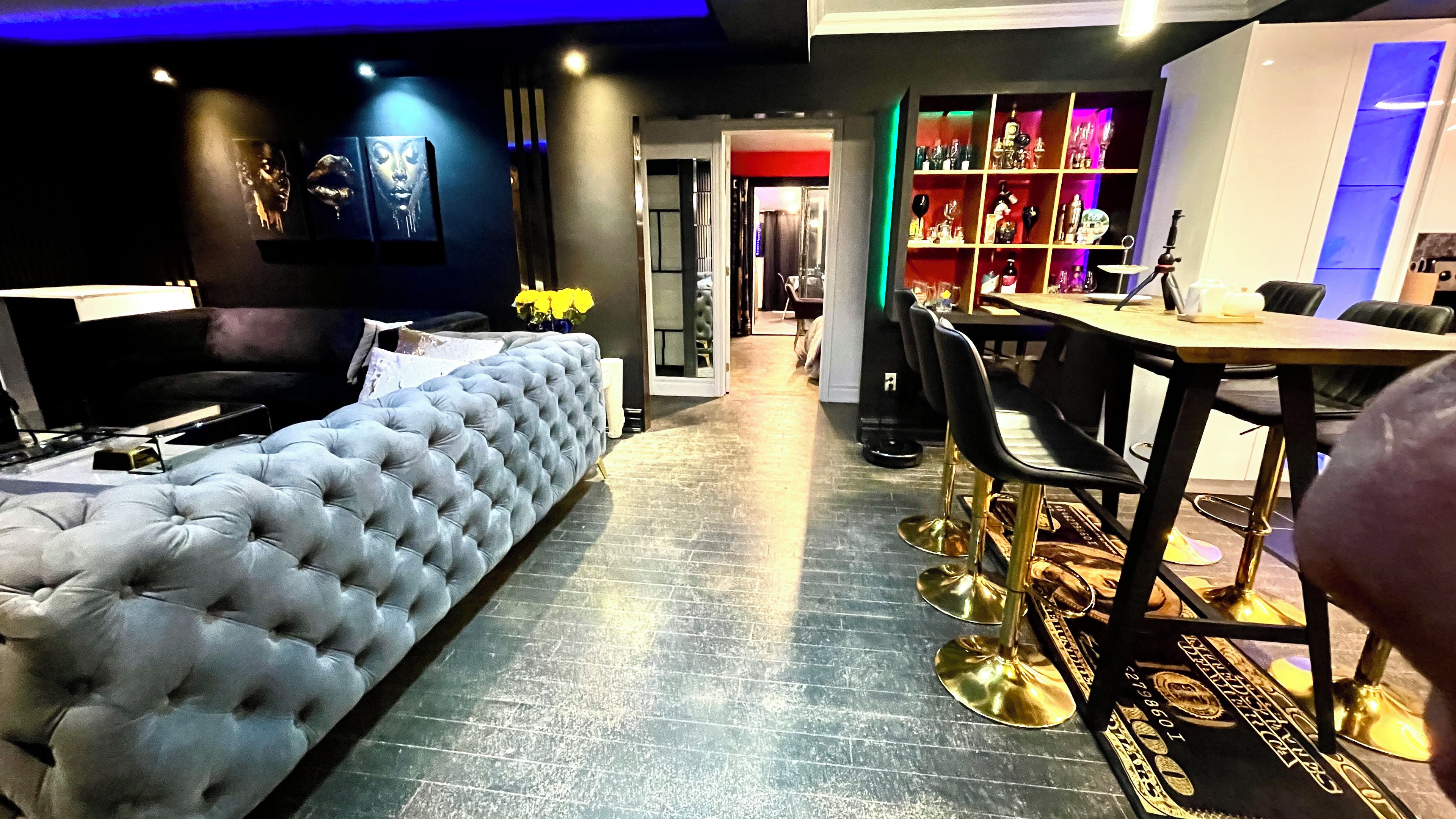 Ein modernes Interieur mit einem gepolsterten Sofa, einem Essbereich mit Tisch und Stühlen sowie einer Bar mit Regalen.
