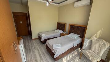 Habitación de hotel con dos camas, una silla, un armario y un equipo de aire acondicionado.