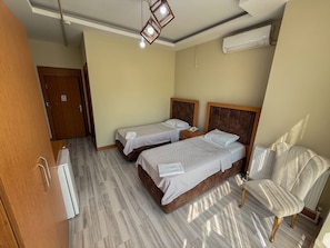 A hotel room with two beds, a chair, a wardrobe, and an air conditioning unit. - AY HANEDAN HOTEL (Osmangazi /bursa)