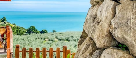 Un mur de pierre, une clôture en bois et une vue sur l’océan.