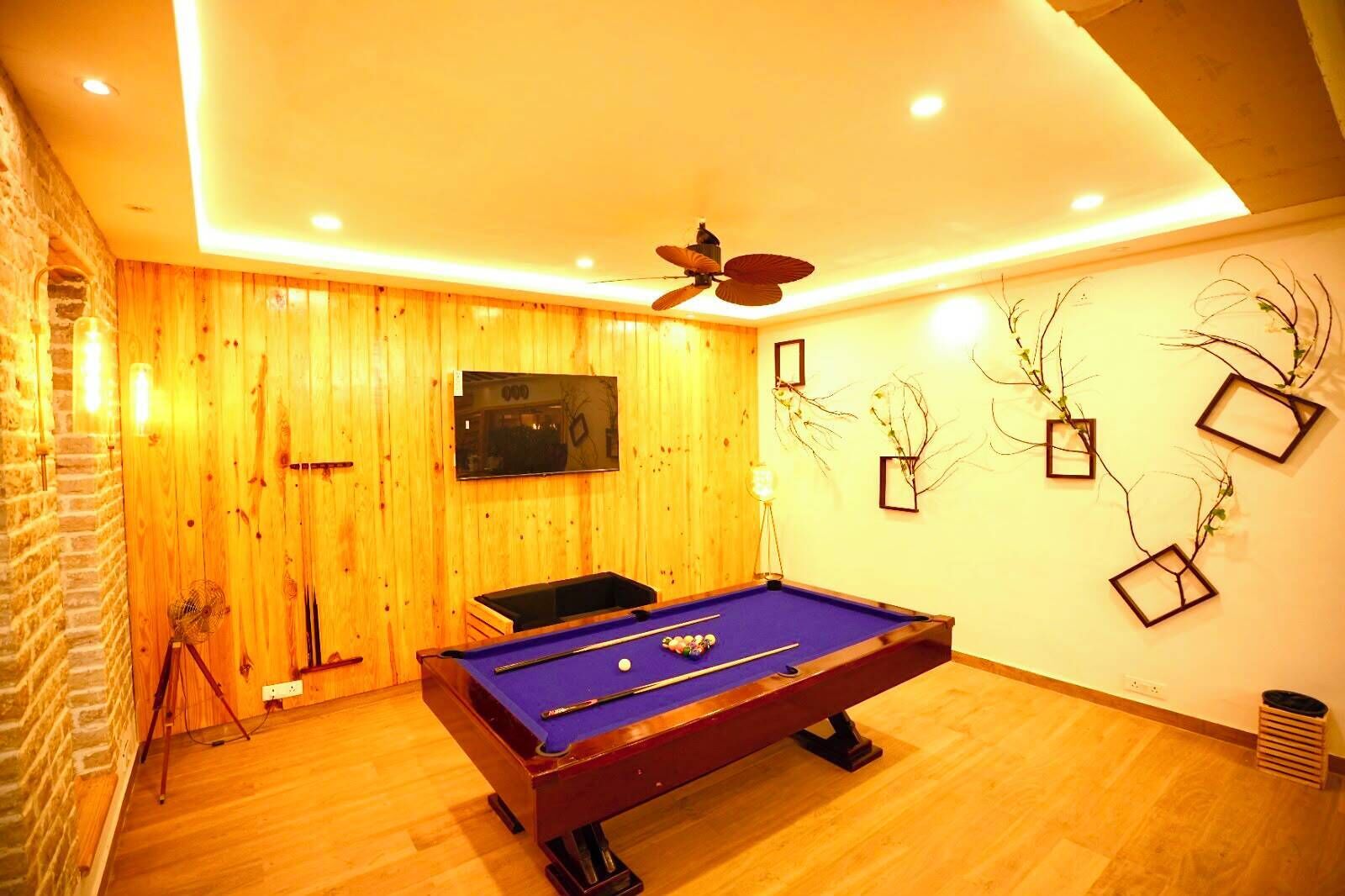 Una mesa de billar en una habitación con paredes de madera, un ventilador de techo y adornos en la pared.