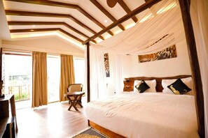 A hotel room with a large bed, a wooden headboard, a desk, and a chair. - Baagh In The Wild Resort & Spa (Rajnagar)