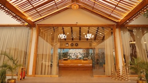 Una zona de recepción con techo de madera, puertas de cristal y un banco.